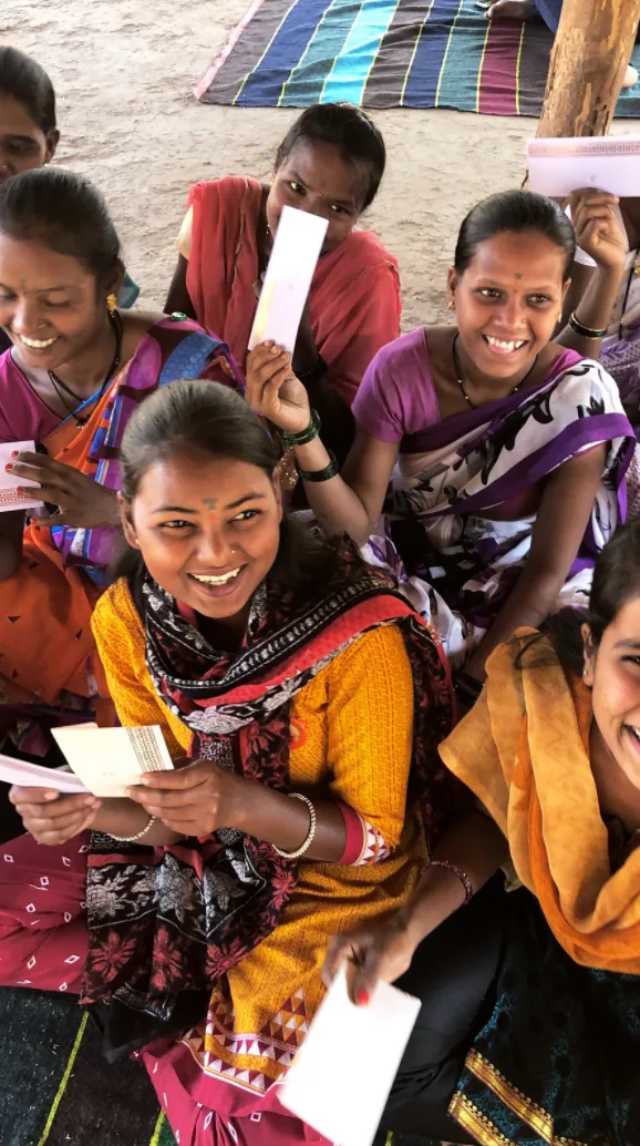 A Karya worker holding her task sheet, laughing with the group